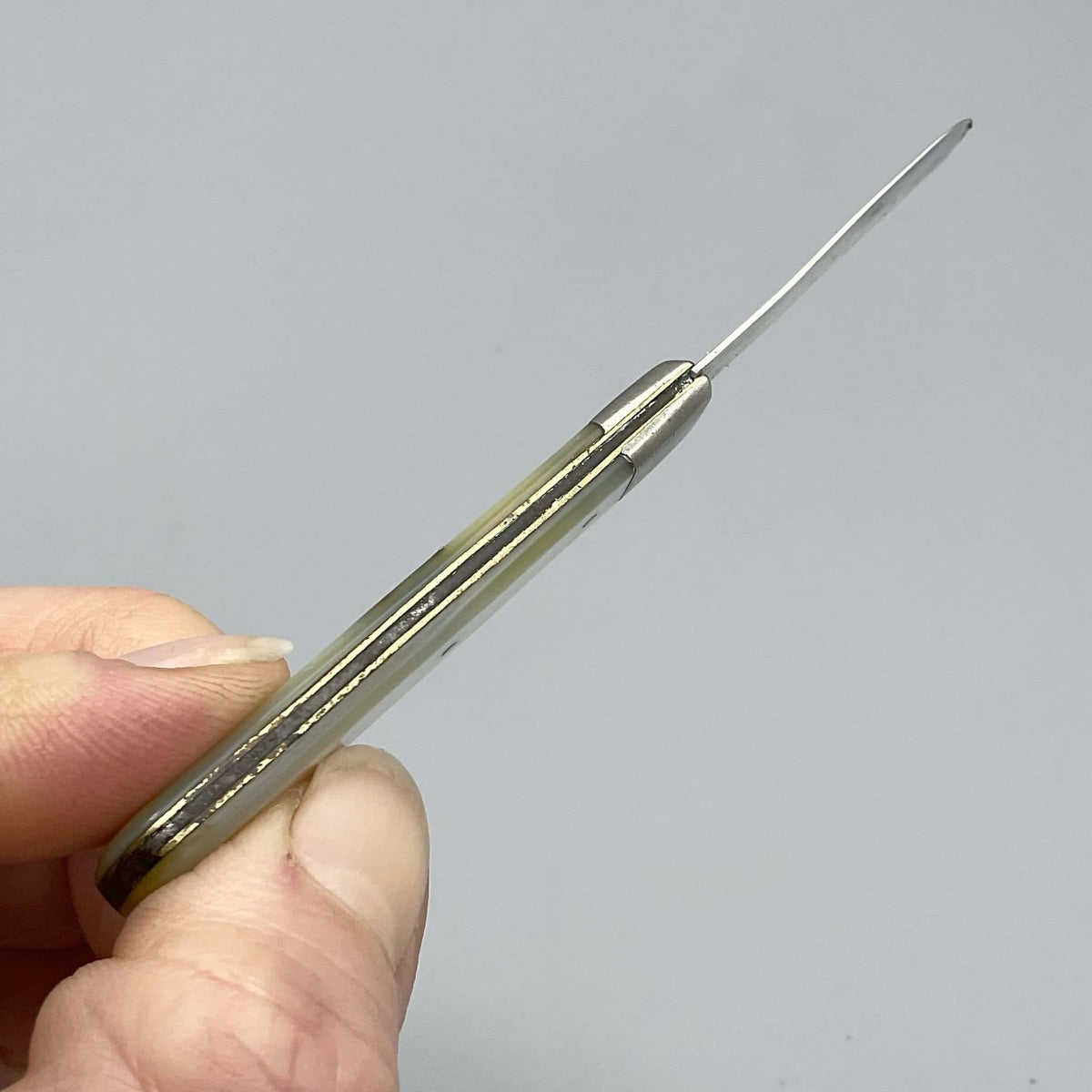 Top view of Silver fruit knife with a mother of pearl handle held in a hand 