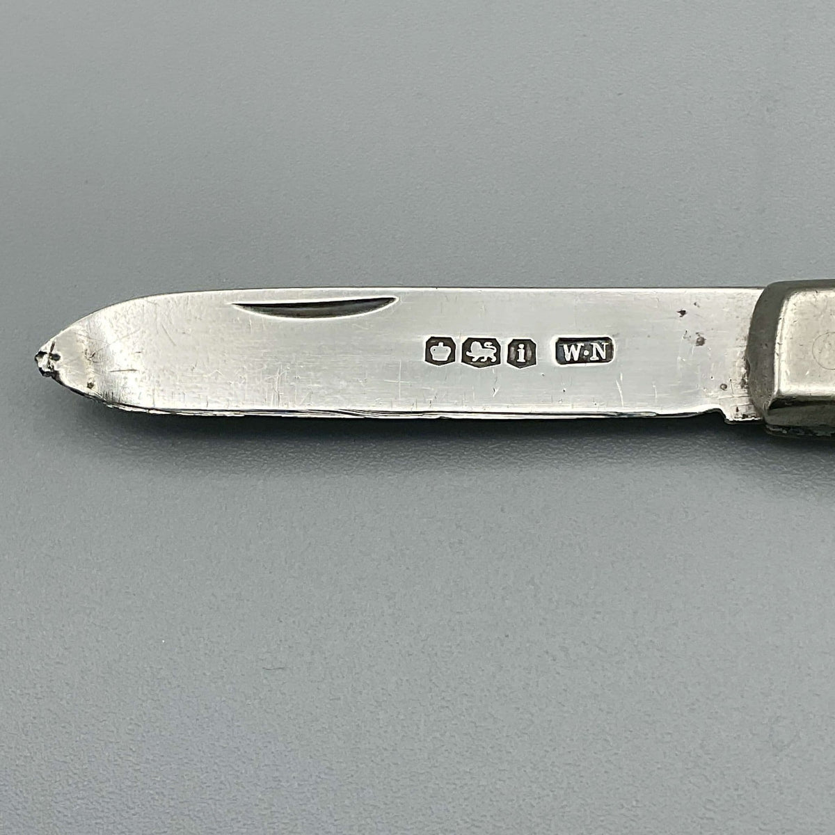 Silver fruit knife blade showing the hallmarks on a grey background