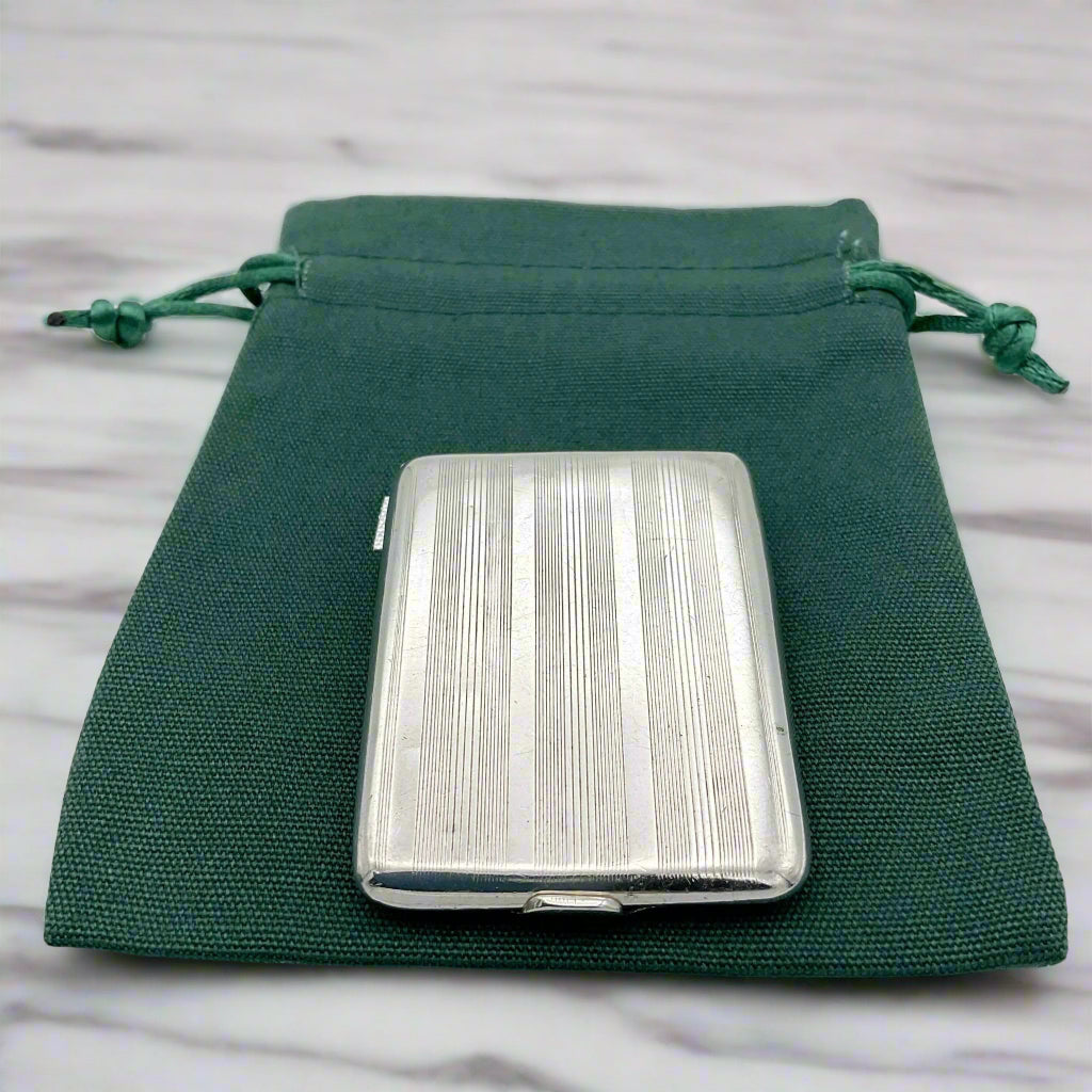 Back view of Silver matchbook case with a lined pattern on a green cotton bag.