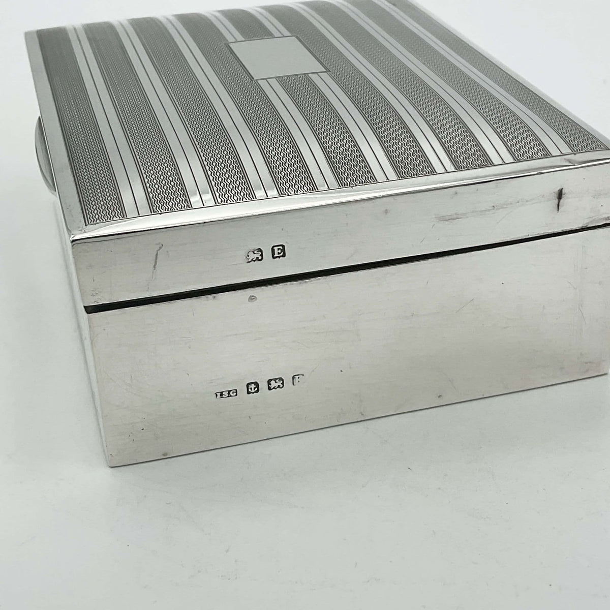 Side view of 1920s vintage silver cigarette box showing the Birmingham hallmarks and makers mark