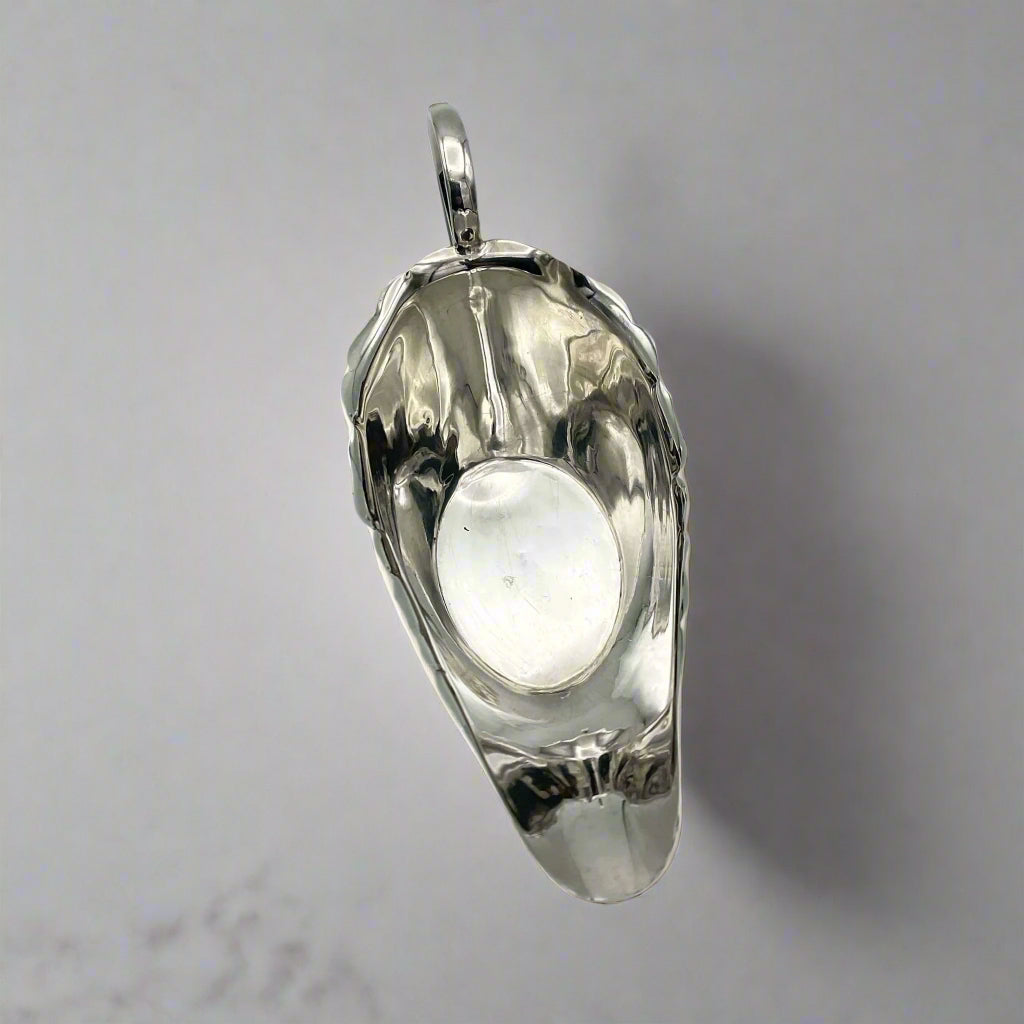 View of inside of silver gravy boat on a marble surface