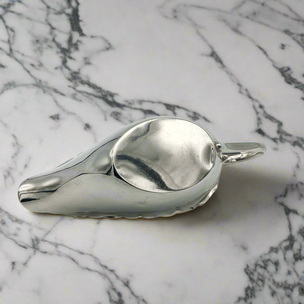 Base of silver gravy boat on a marble surface
