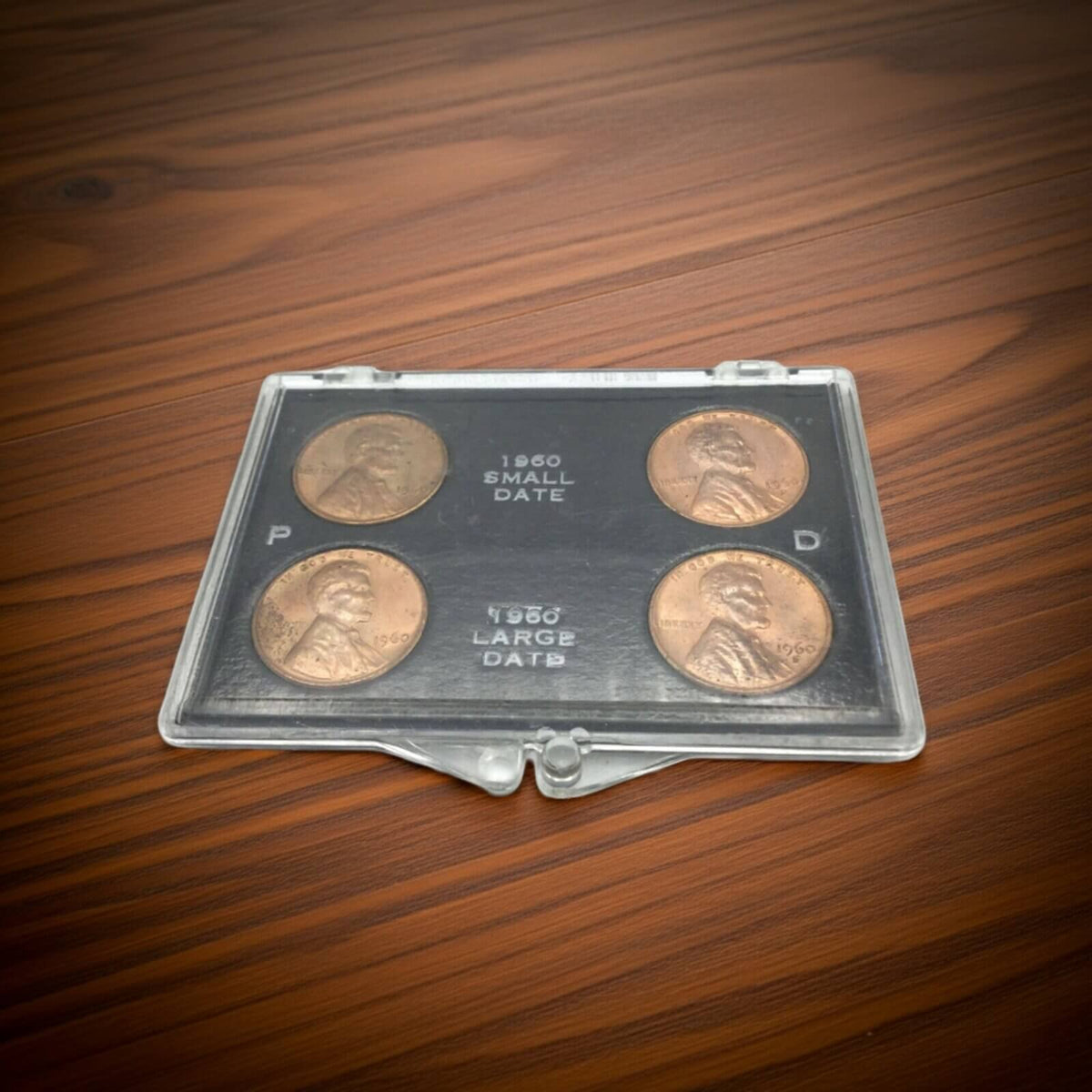 Set of four coins in a clear plastic case on a wooden surface