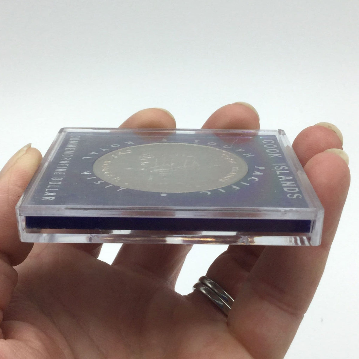Cook Islands dollar coin with a ship on it in a blue case from side view