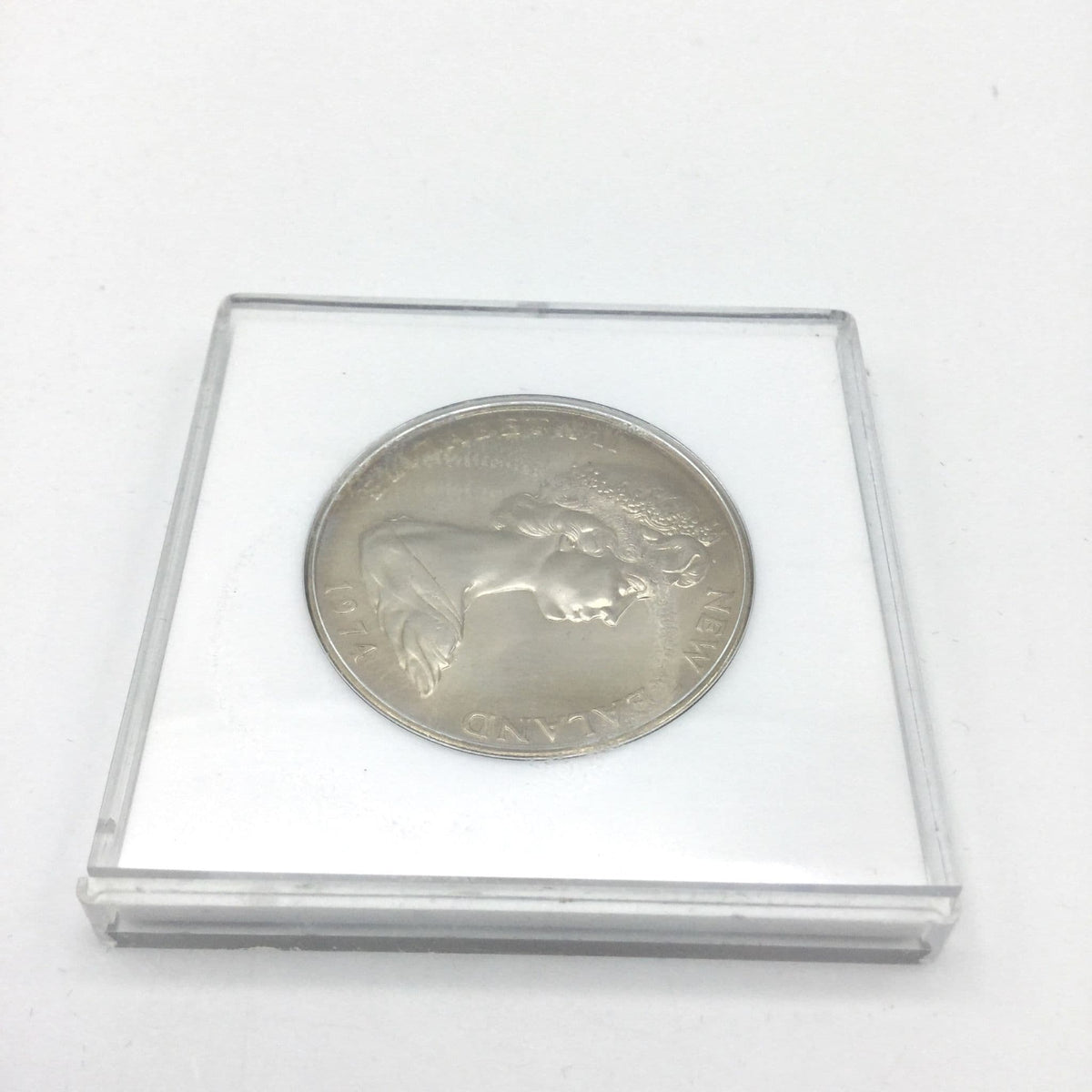 Reverse view of One dollar coin in a white case on a marble worktop