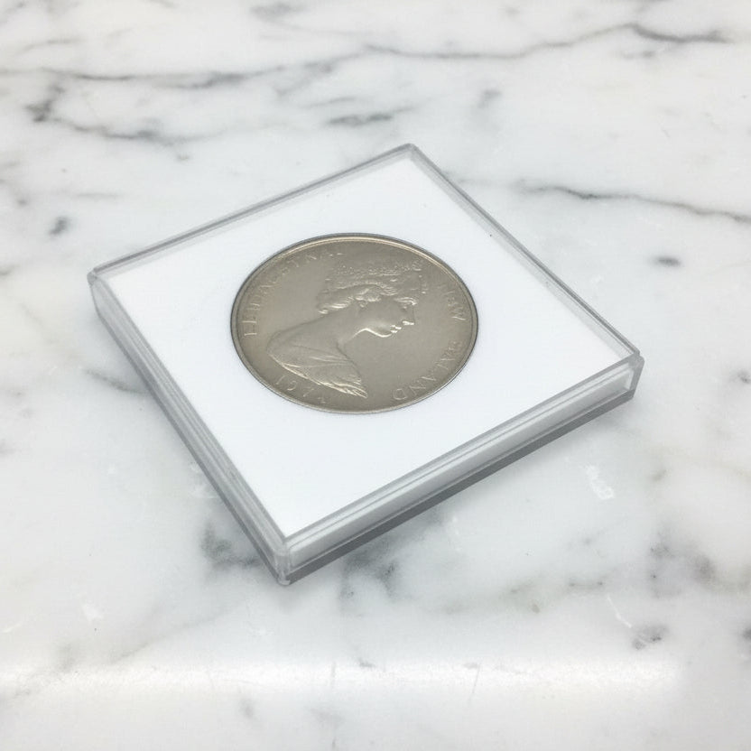 Silver coin in a protective case on a marble surface