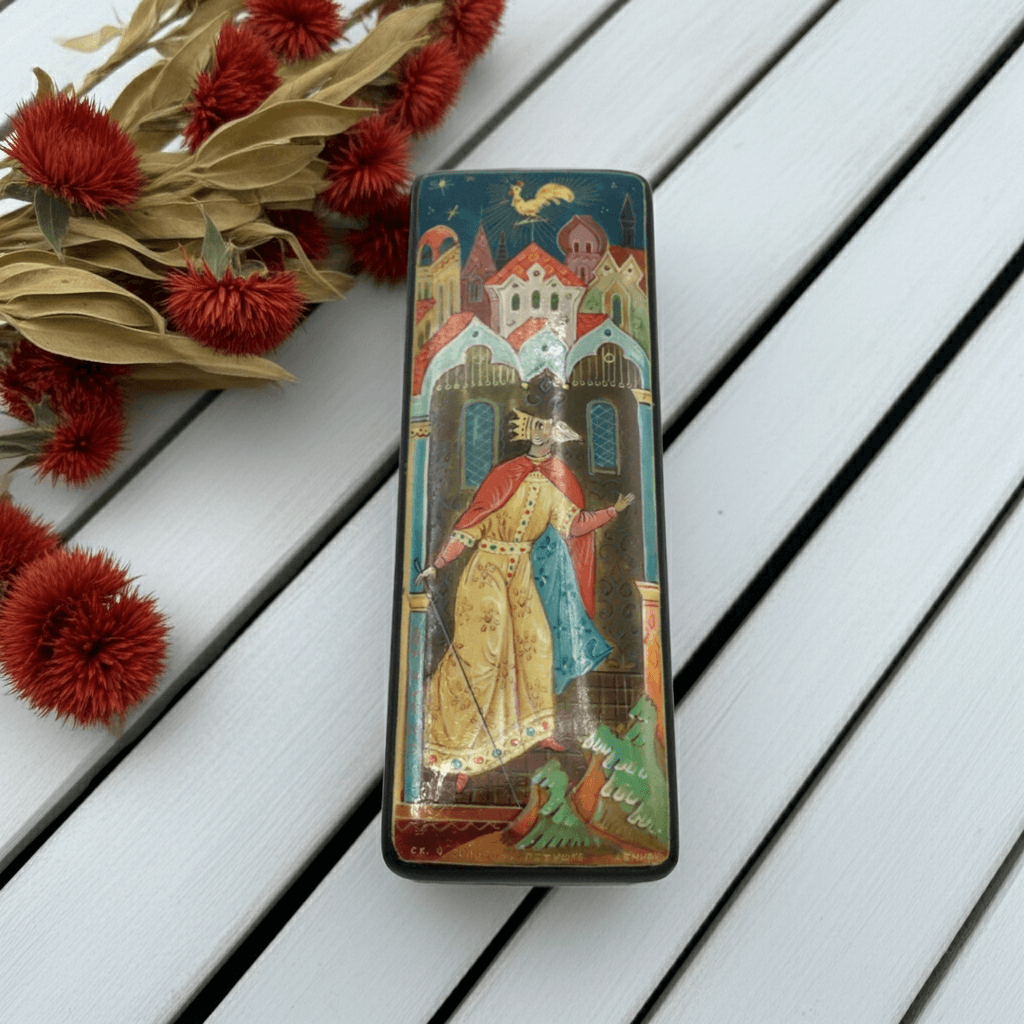 Decorative box with artistic enamel on a wooden surface with red flowers.