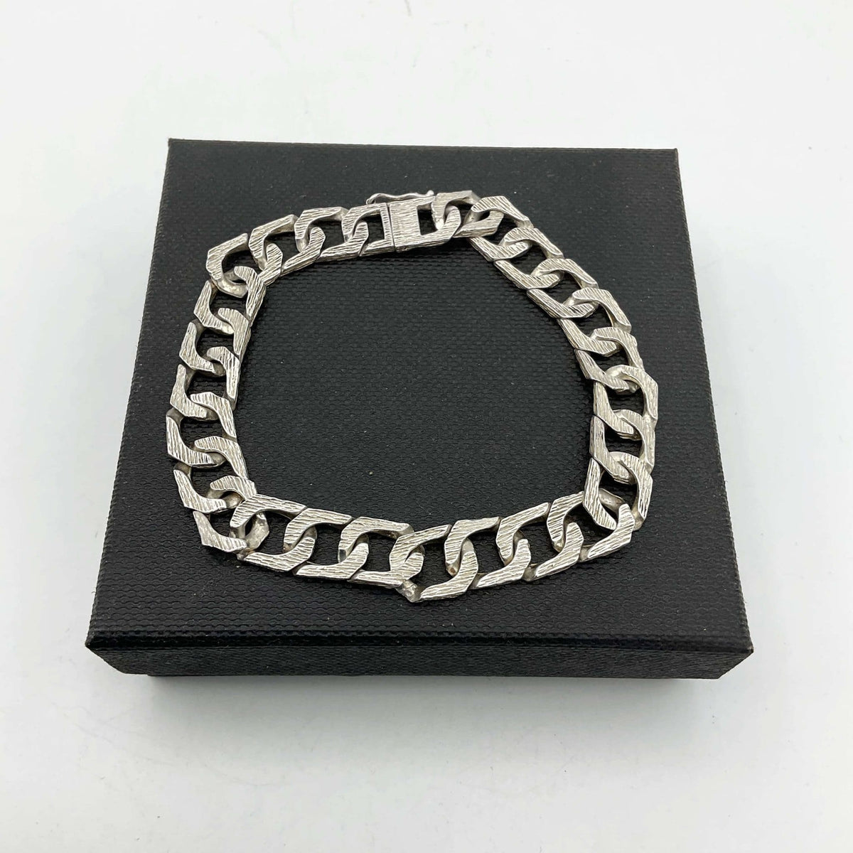 silver chain bracelet lying flat on a black presentation box