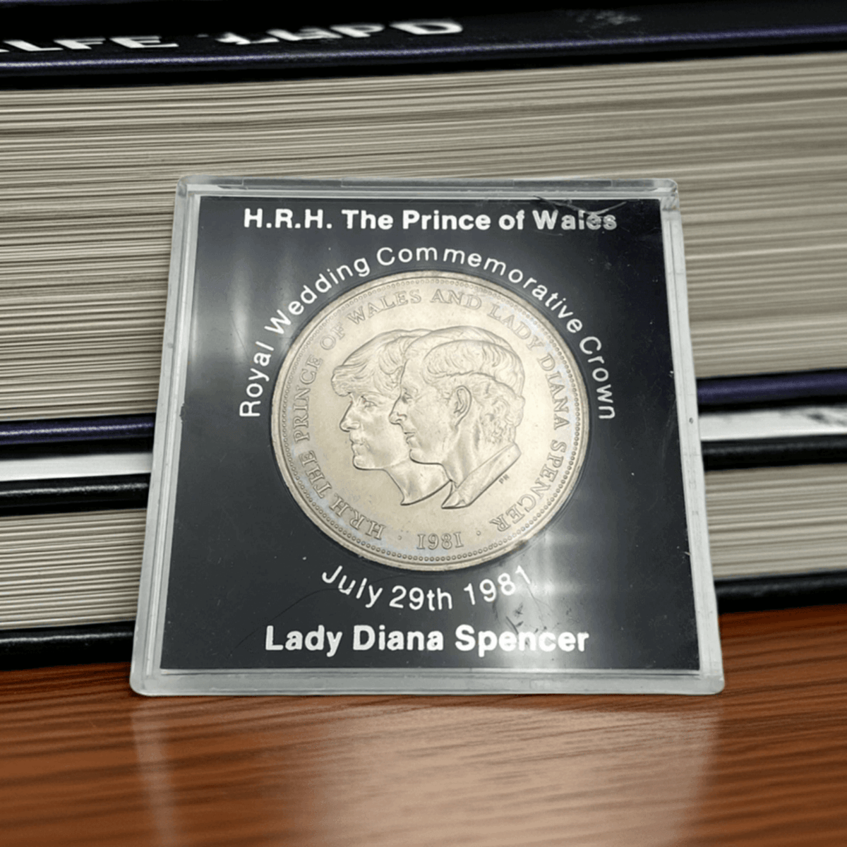 Royal wedding commemorative coin in a clear case with text on a wooden surface