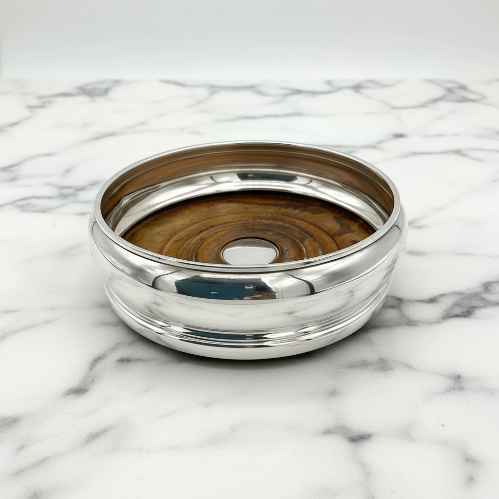silver bottle coaster with wood interior on a marble worktop