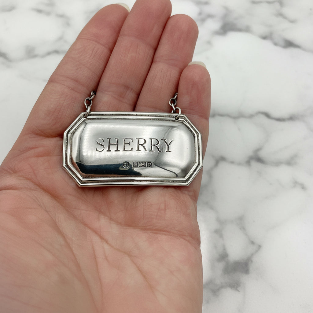 Sherry decanter label held in a hand with a marble background