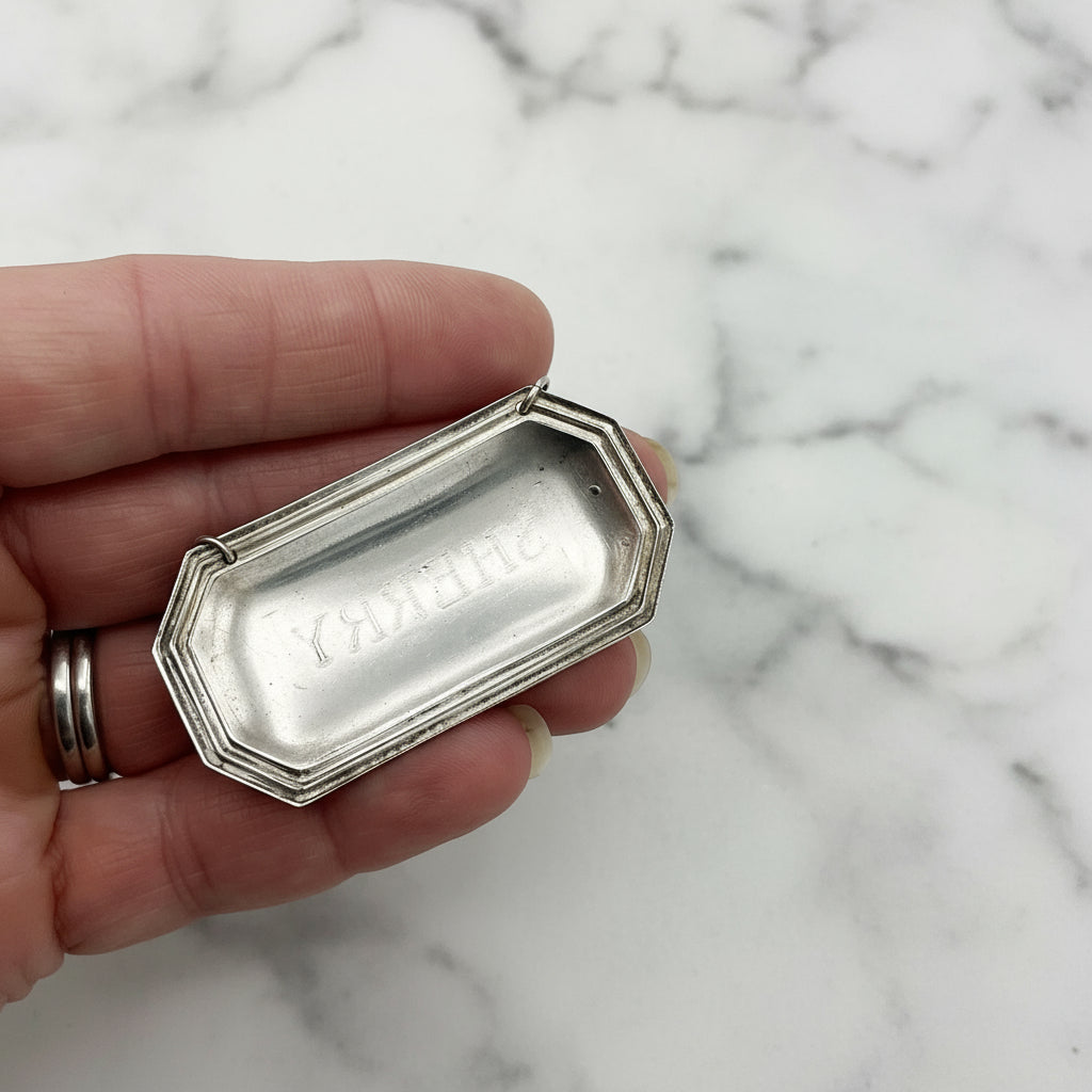 back of silver sherry label held in fingers with a marble background