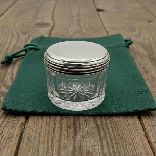 Glass jar with silver lid on a green cloth over a wooden surface