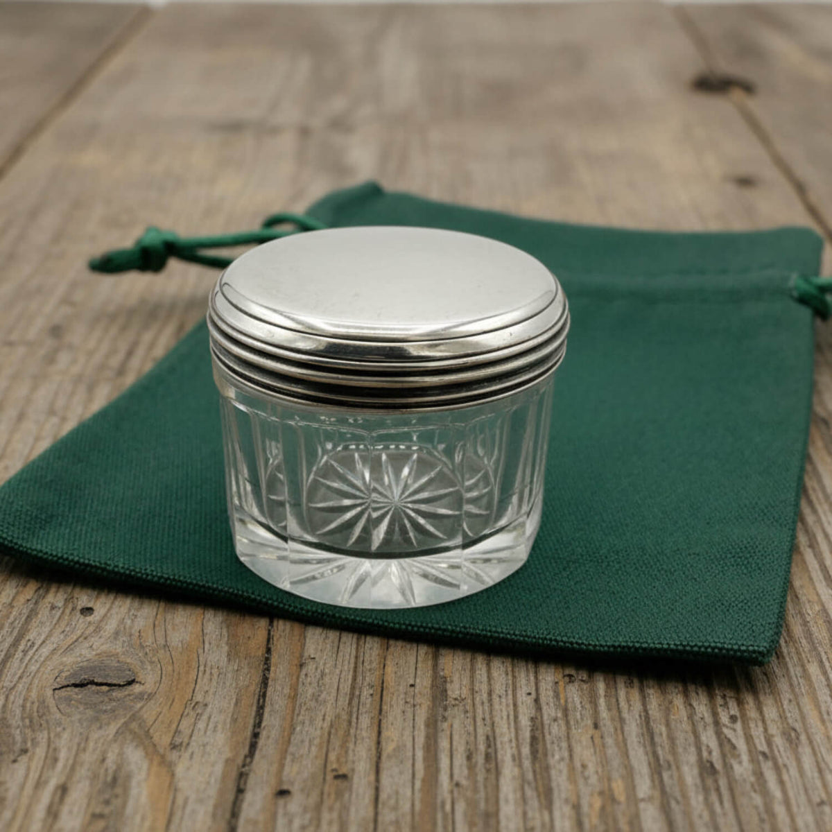 Glass jar with silver lid on a green cloth bag over a wooden surface