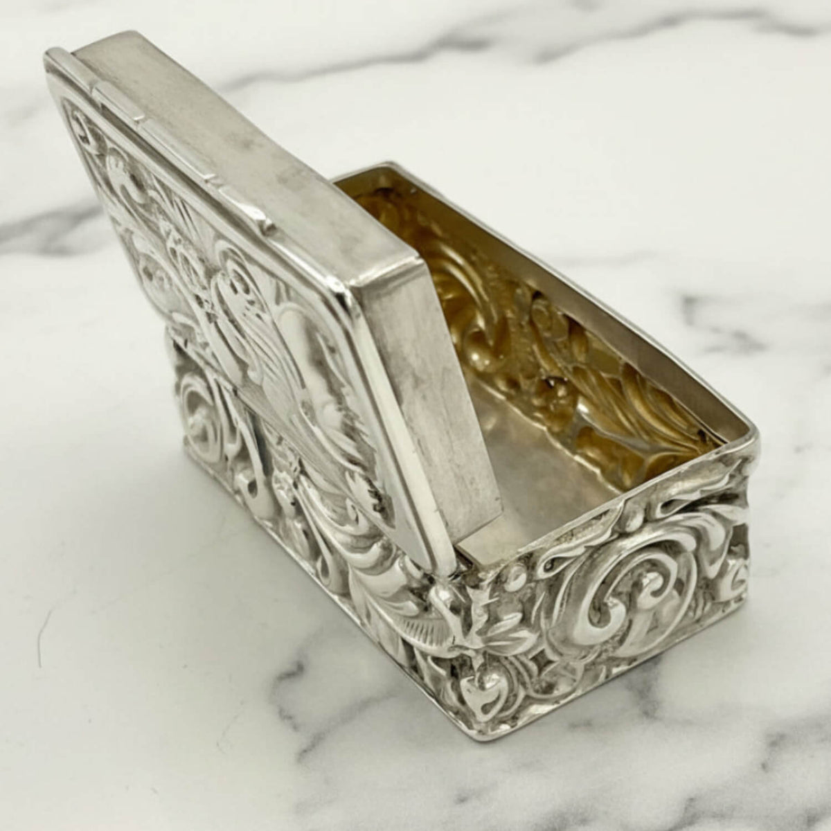 Decorative silver box with intricate designs on a marble surface