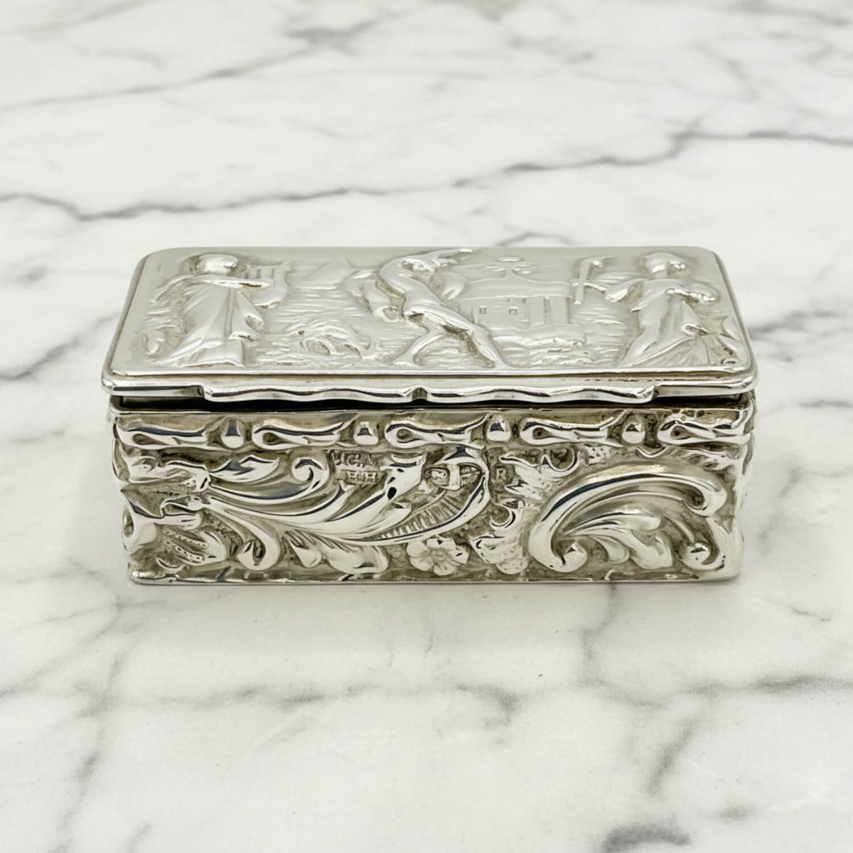 Decorative silver box with intricate designs on a marble surface