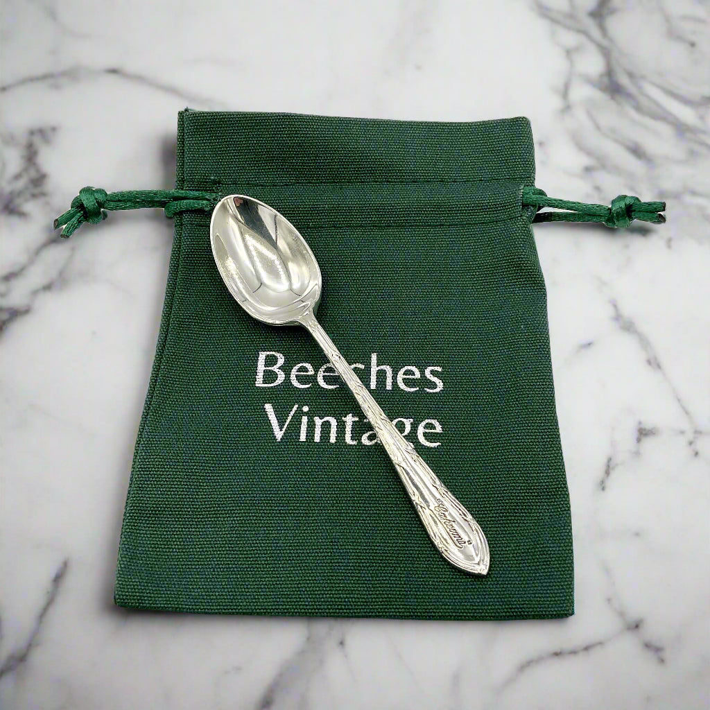 Silver spoon on a green drawstring bag with 'Beeches Vintage' text on a marble worktop