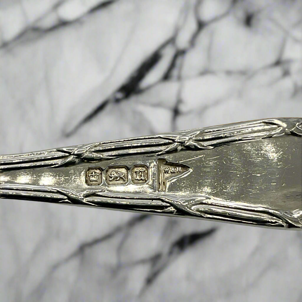 Close-up of a silver spoon with hallmarks on a marble background 