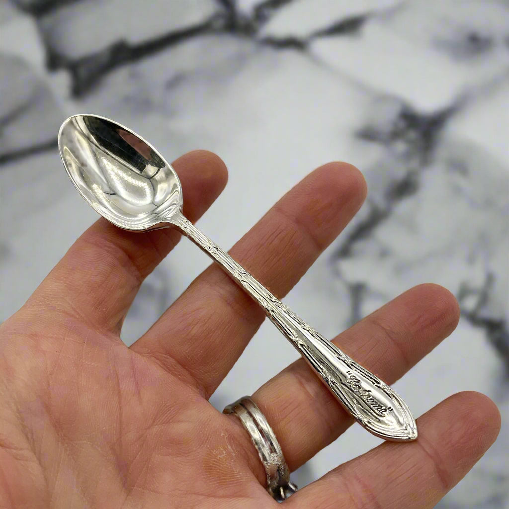 Silver spoon held in a hand with a marble background