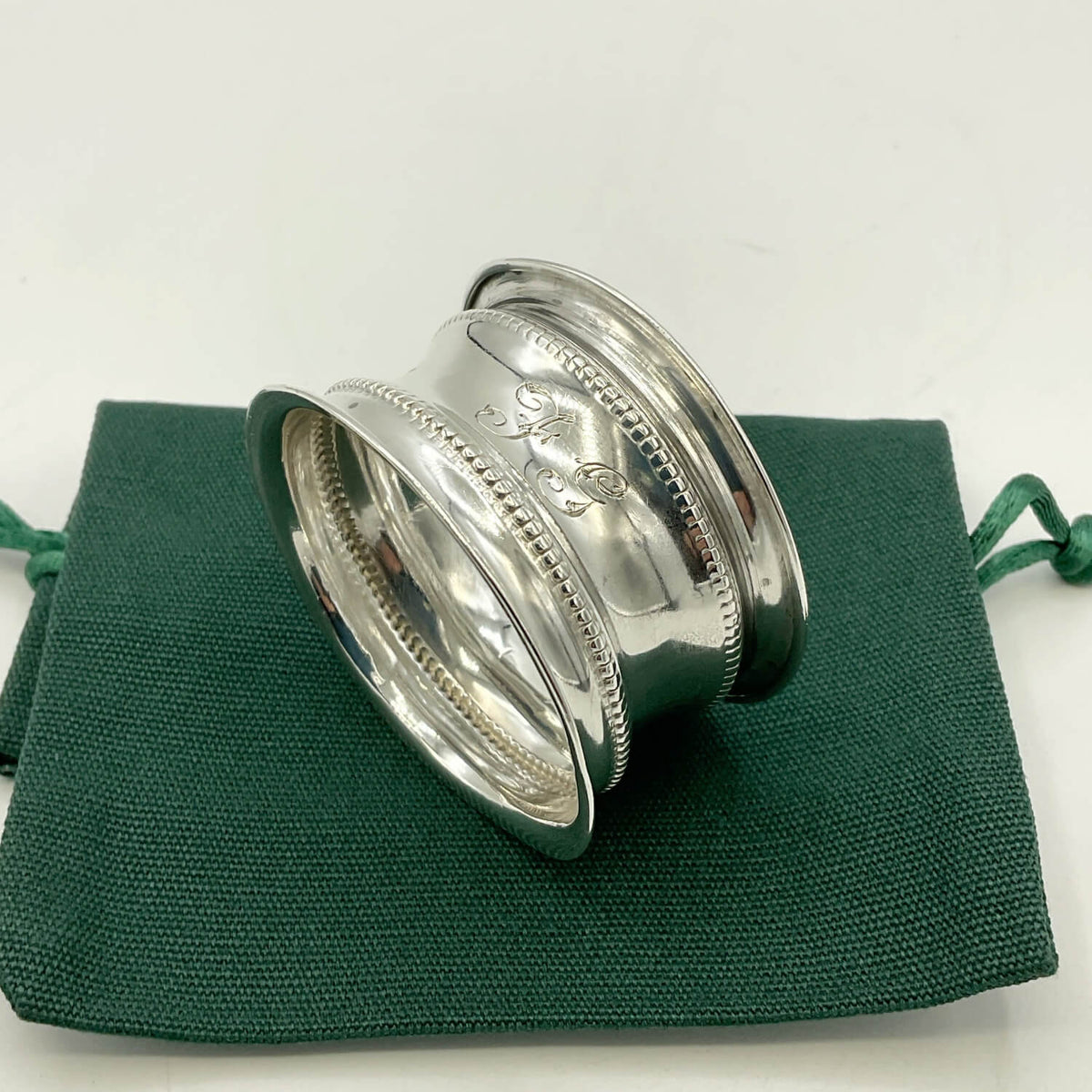 Antique 1912 Sterling Silver Napkin Ring on a green bag 