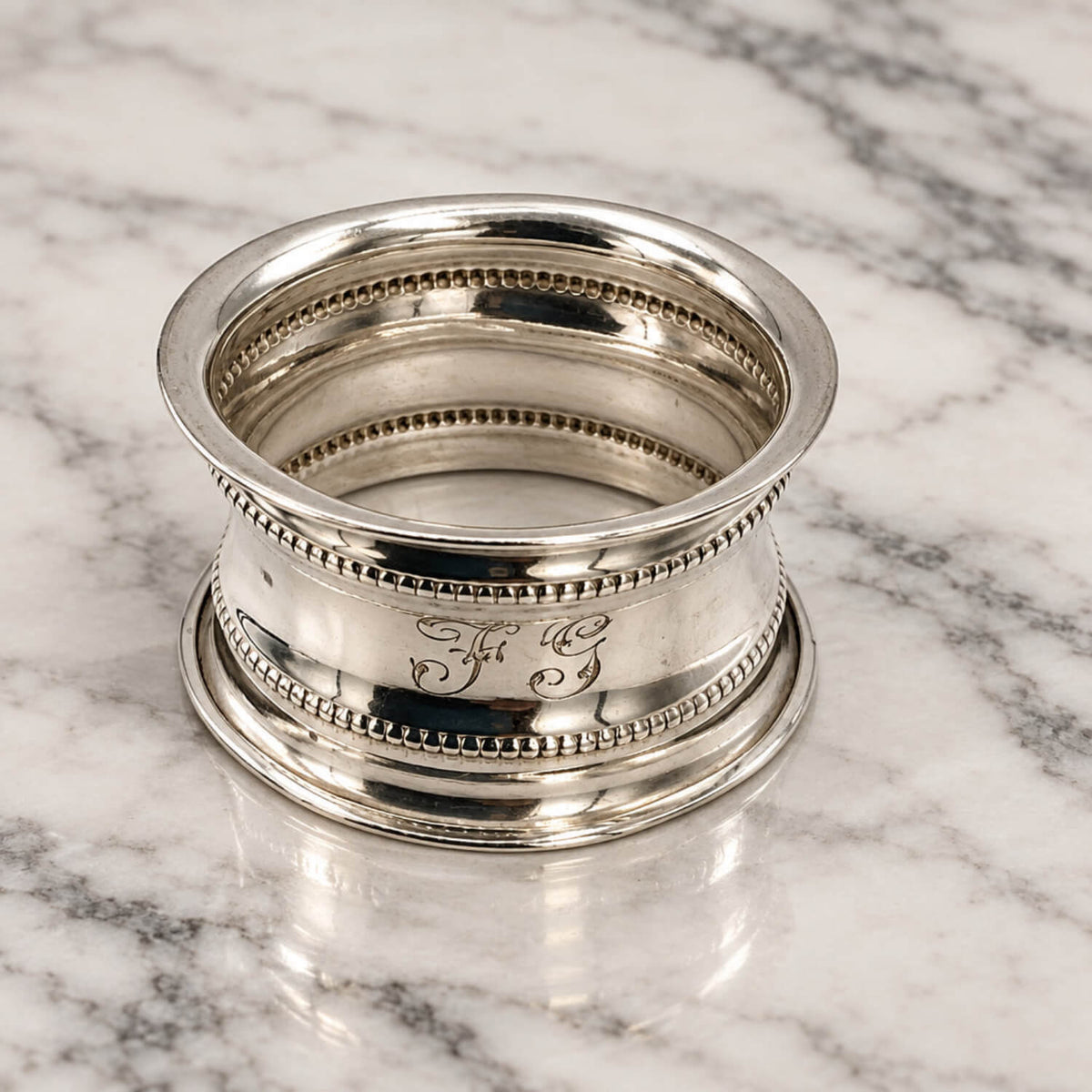 Antique 1912 Sterling Silver Napkin Ring on a marble surface