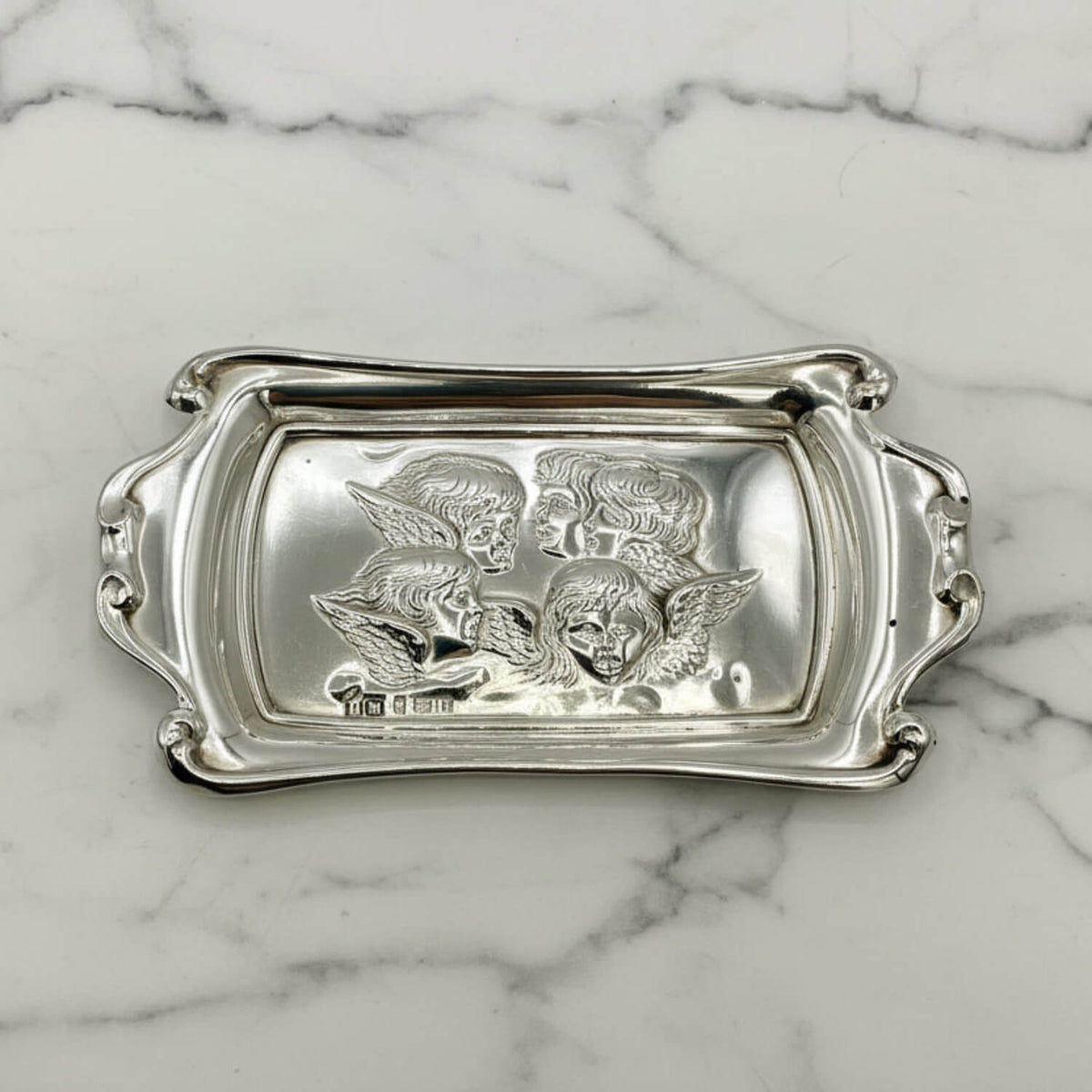 Silver tray with engraved designs on a marble surface