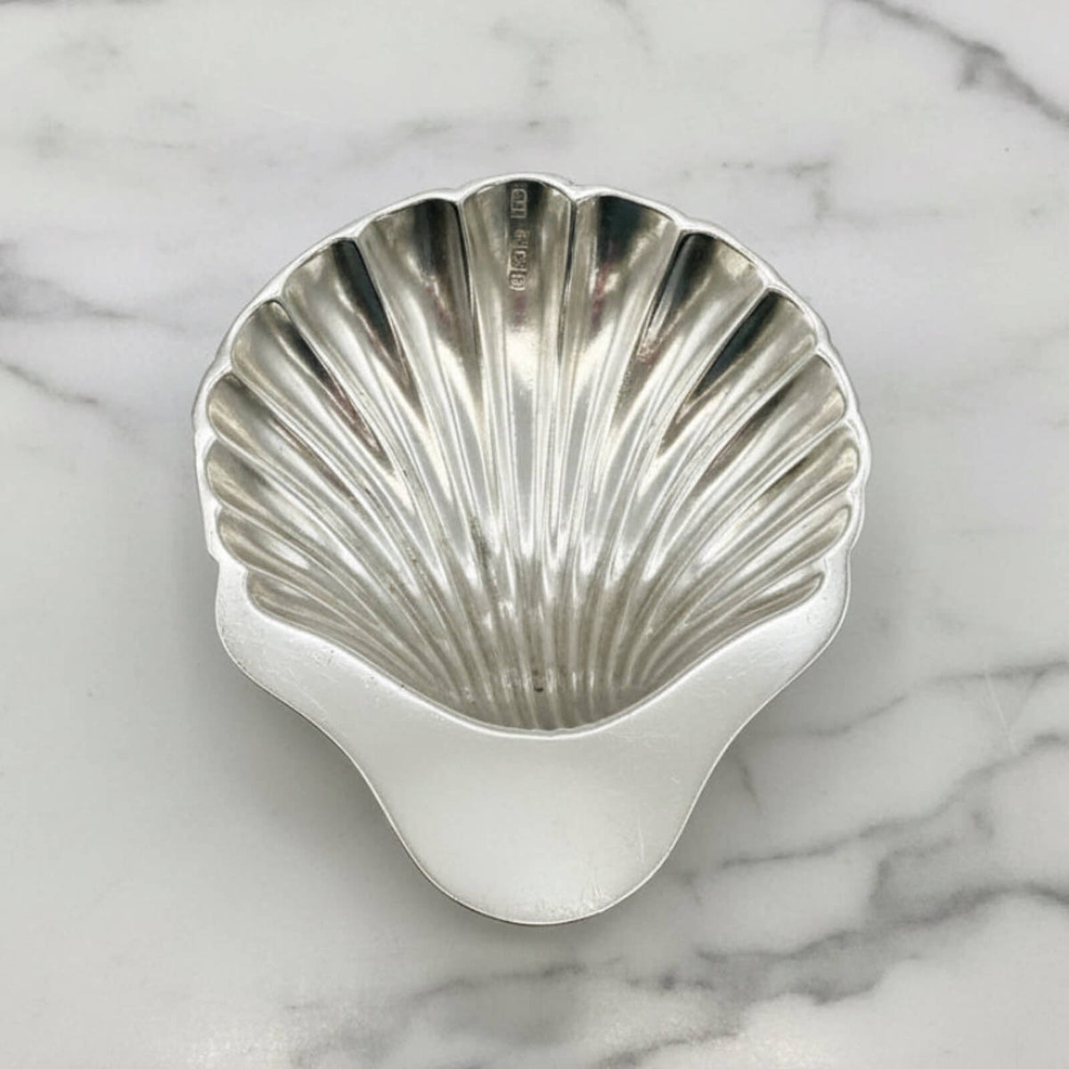 Silver shell-shaped bowl on a marble surface