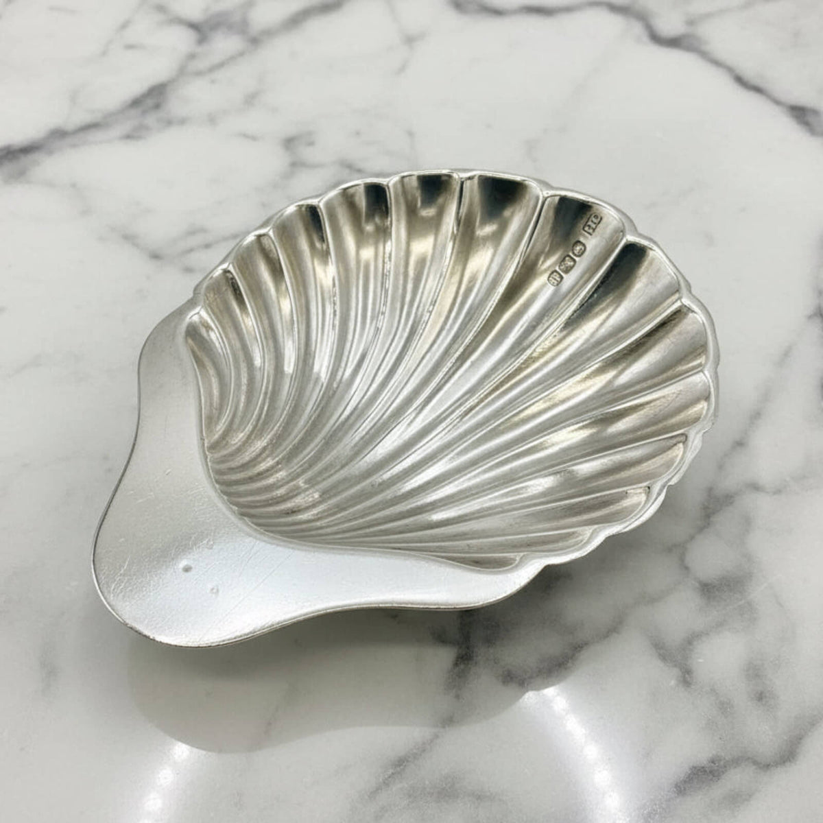 Silver shell-shaped dish on a marble surface