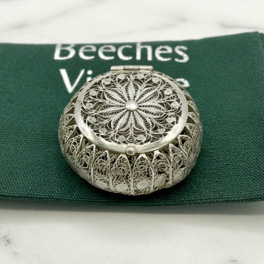 Silver filigree compact mirror on a green fabric background with 'Beeches' branding.