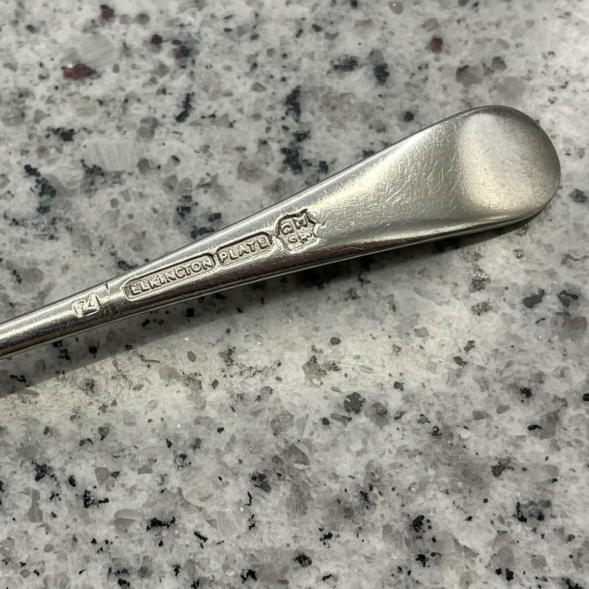 Silver spoon with 'Elkington & Co.' and Elkington Plate on a speckled grey surface