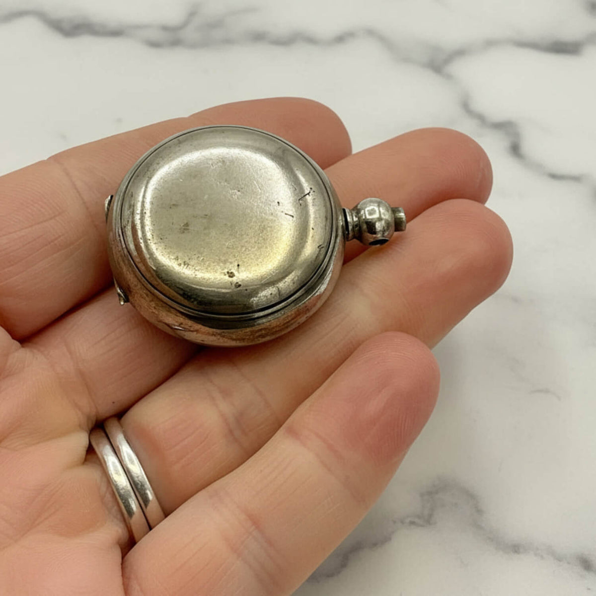 Antique Silver Plated Sovereign Case held in a hand against a marble background