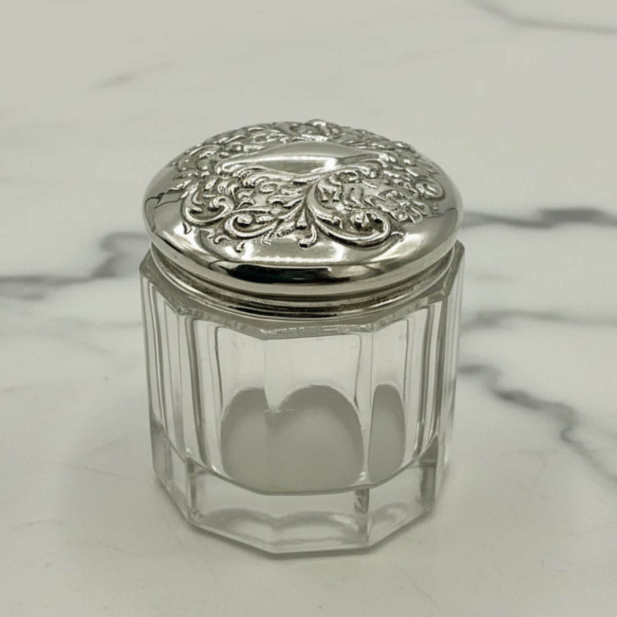 Clear glass jar with a silver lid on a marble surface