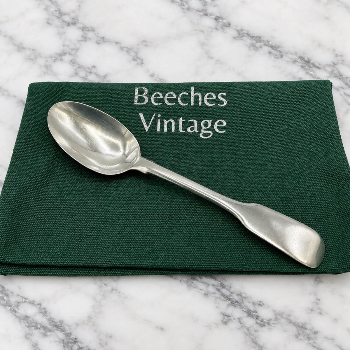 Antique Victorian Sterling Silver Teaspoon on a gift bag and marble surface