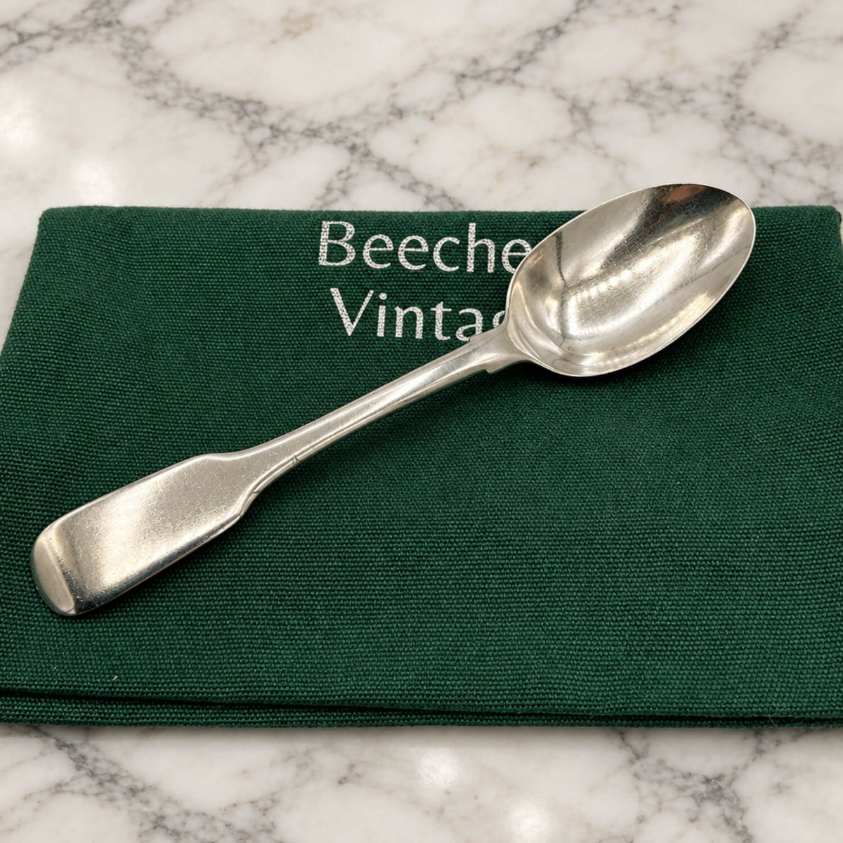 Antique Victorian Sterling Silver Teaspoon on a gift bag and marble surface