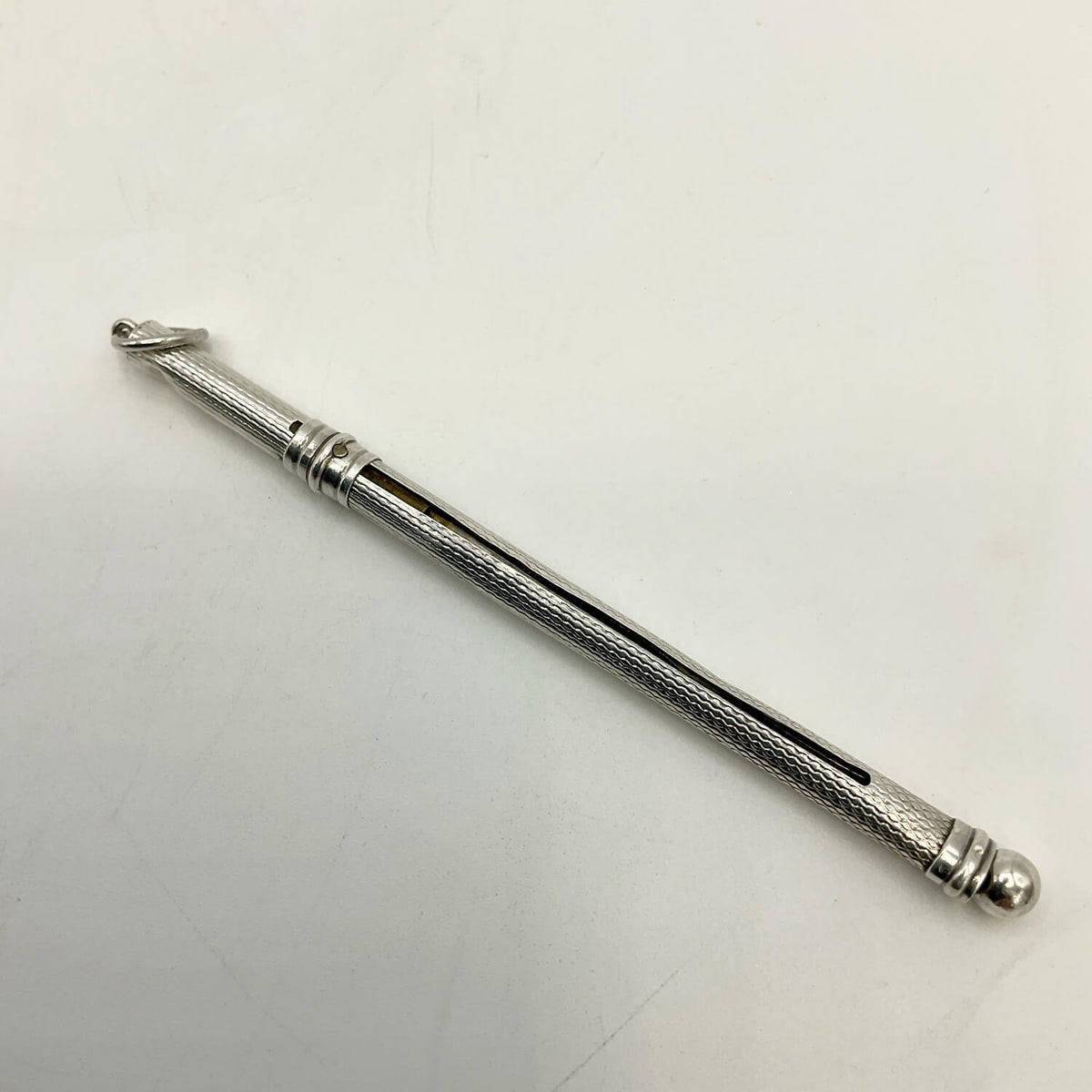 A Art Deco Sterling Silver Cocktail Whisk with a textured grip and a small loop at one end, photographed on a plain light background.