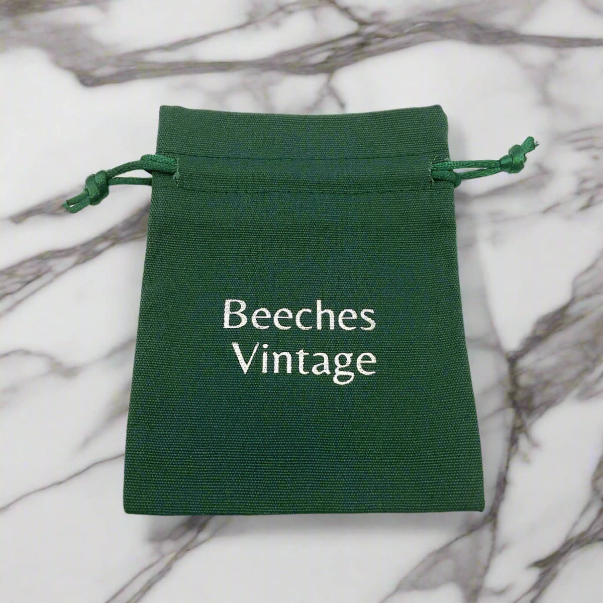 Green drawstring pouch with 'Beeches Vintage' text on a marble background