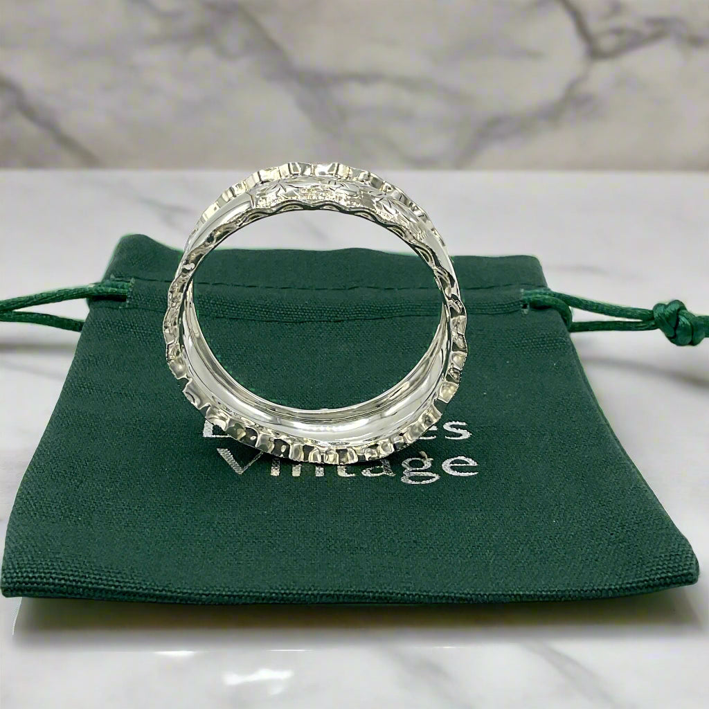 Silver napkin ring on a green bag on a marble worktop