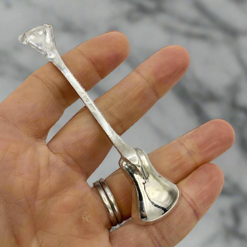 Silver spoon held in a hand with a blurred marble background