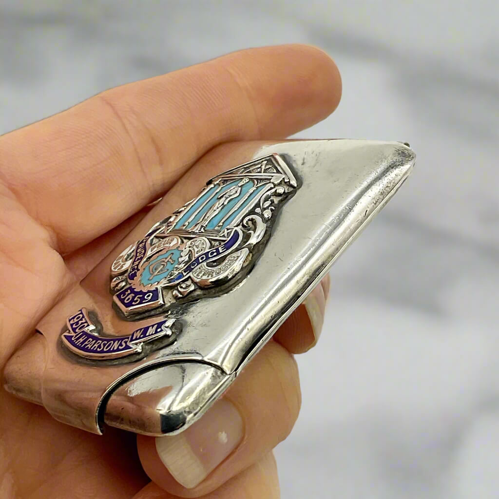 Hand holding a silver and blue decorative silver matchbook case against a marble background