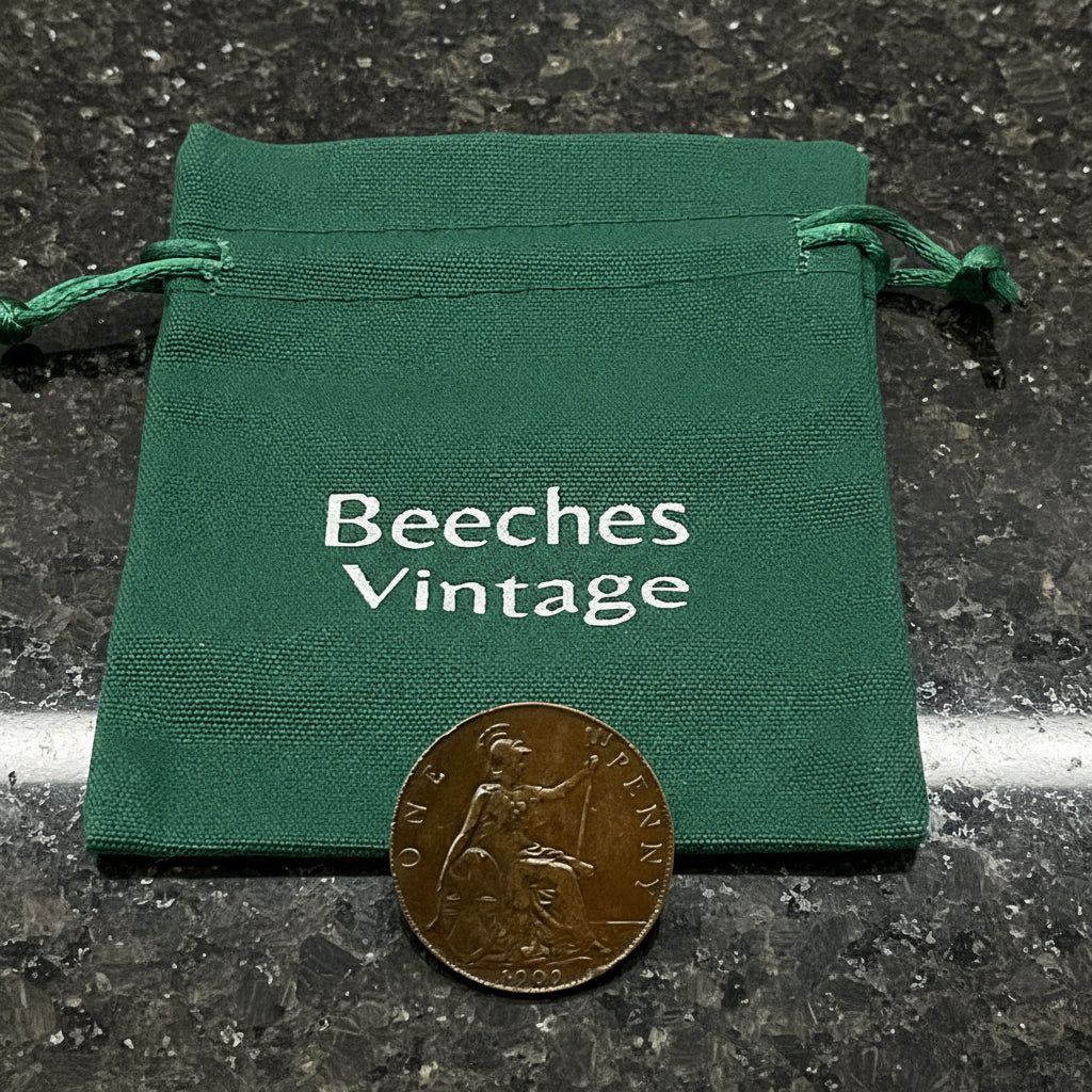Green drawstring bag with 'Beeches Vintage' text and an antique coin on a dark granite background