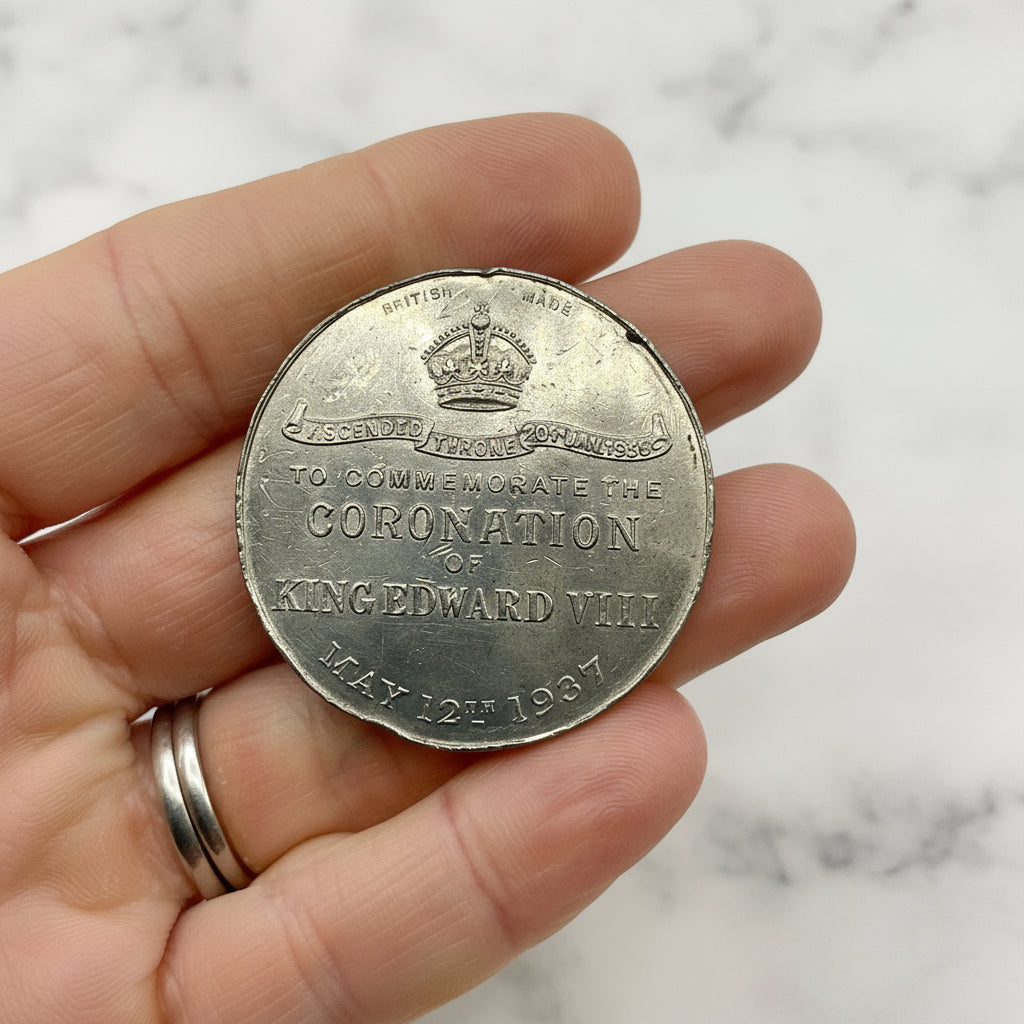Silver coin commemorating the Coronation of King Edward VIII held in a hand.