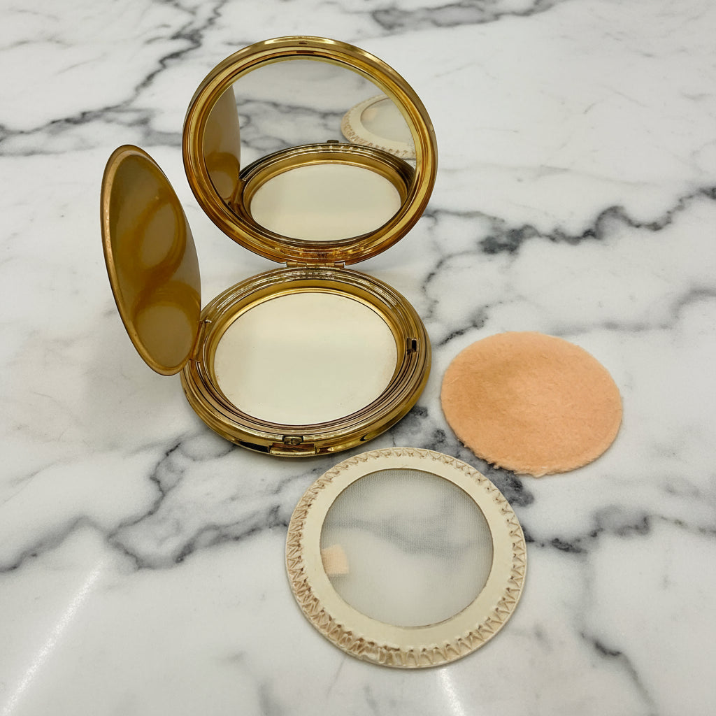 Compact powder with mirror and applicator on a marble background