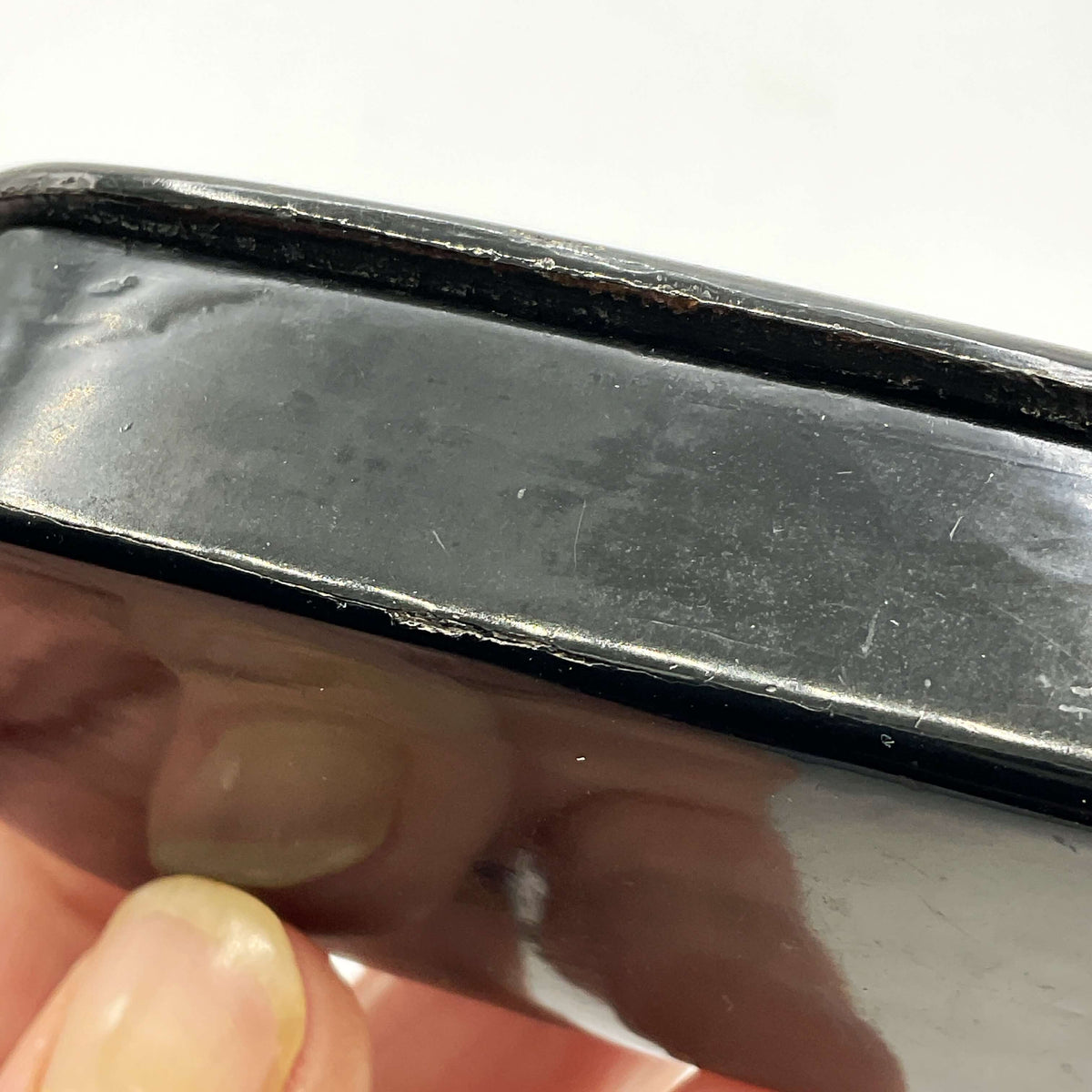 Close-up the edge of a trinket box with a hand holding it against a white background