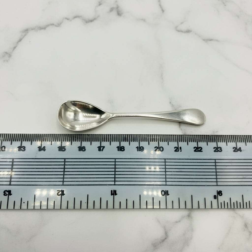 Silver spoon next to a ruler on a marble surface