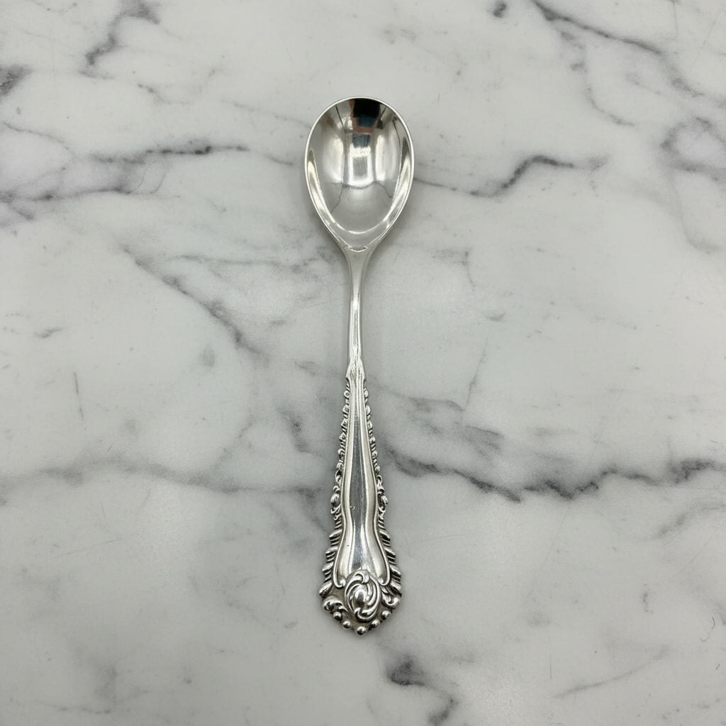 Silver spoon with decorative pattern on a marble background