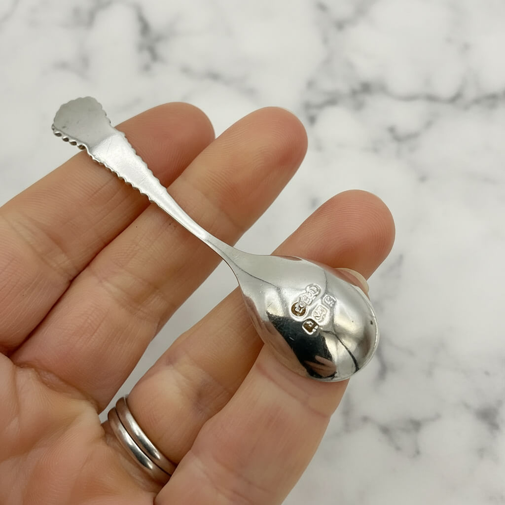 Back of Silver spoon held in a hand against a marble background
