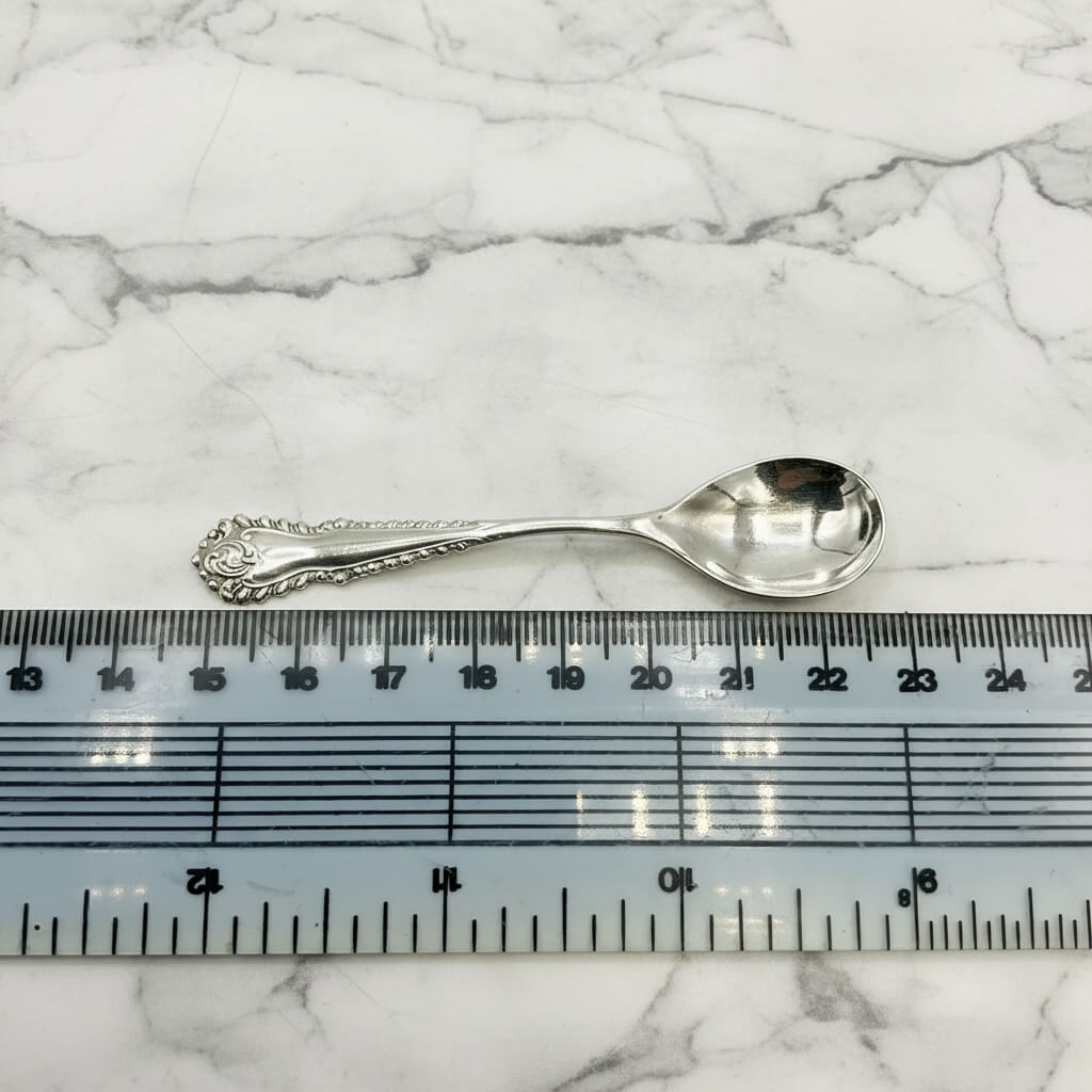 Silver spoon next to a ruler on a marble background