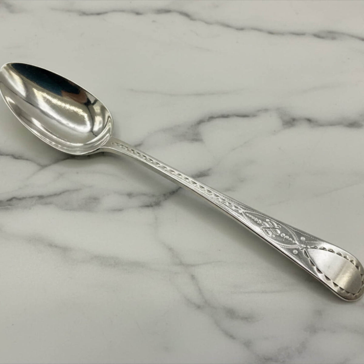 Antique Georgian sterling silver teaspoon with hallmarks from 1793, featuring intricate detailing and classic design.