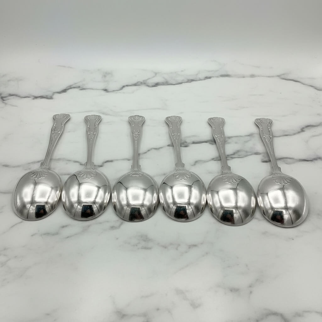 backs of silver plated soup spoons on a marble worktop