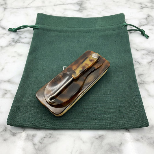 Vintage Shoe Horn Hook and Buffer on a green cotton bag on a marble surface